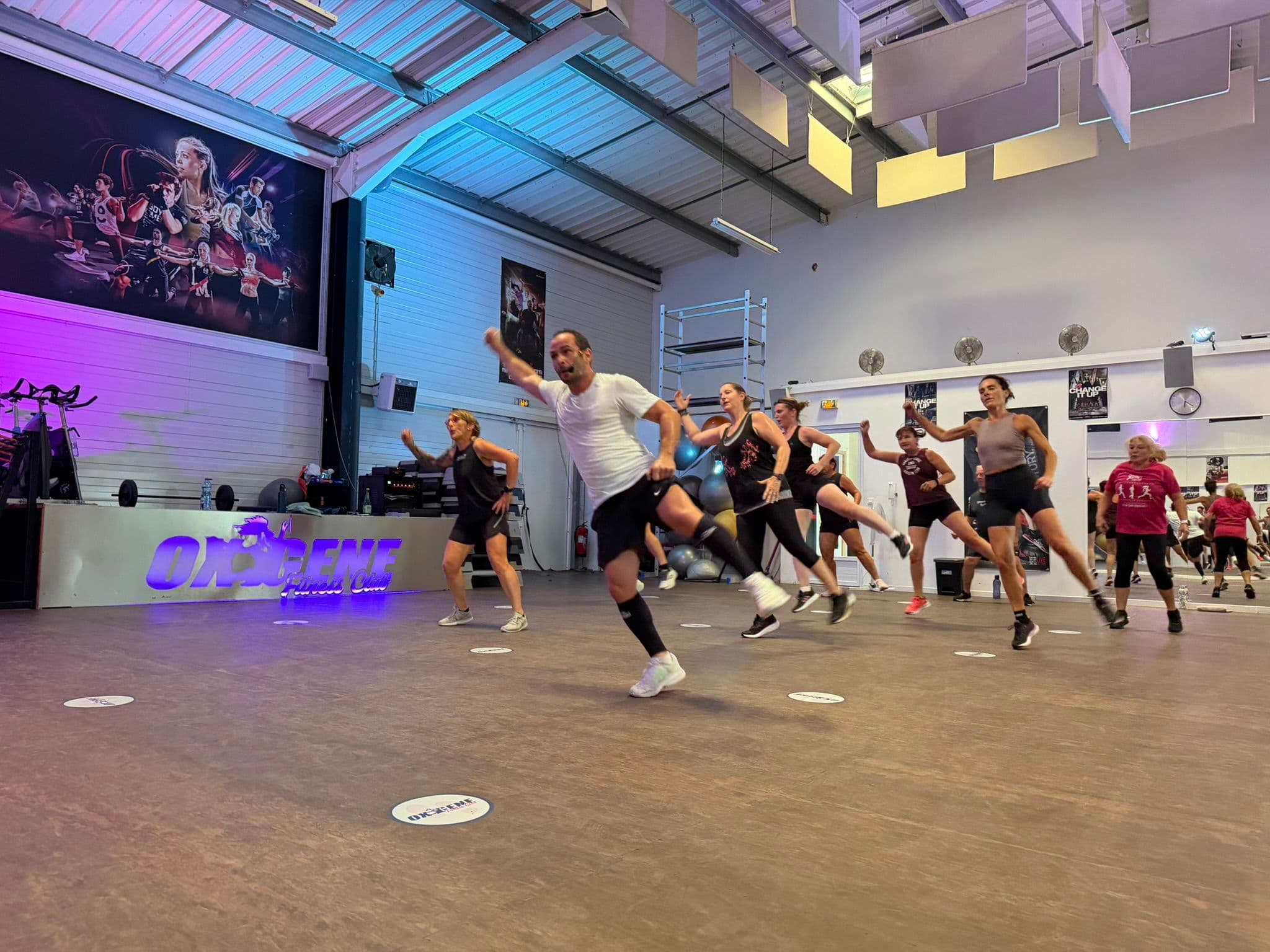 Coach guidant un groupe d’adhérents pendant une séquence dynamique à OXYGÈNE Fitness Saint-Macaire.