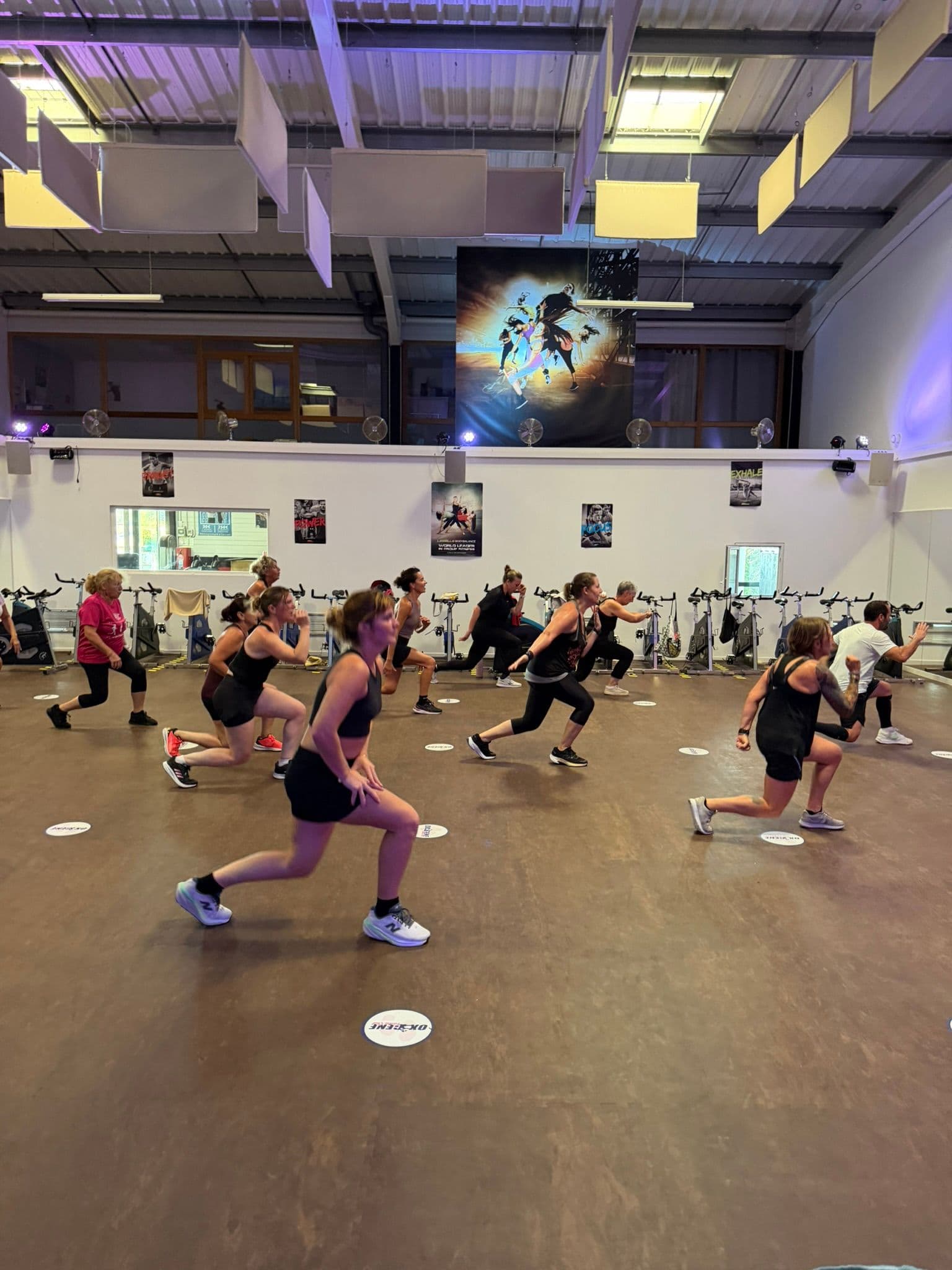 Groupe d’adhérents réalisant des fentes pendant un cours collectif à OXYGÈNE Fitness Saint-Macaire.