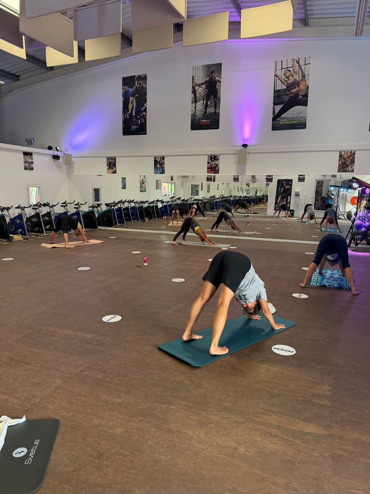 Adhérents réalisant des mouvements d’étirement sur des tapis pendant un cours collectif à OXYGÈNE Fitness Saint-Macaire.