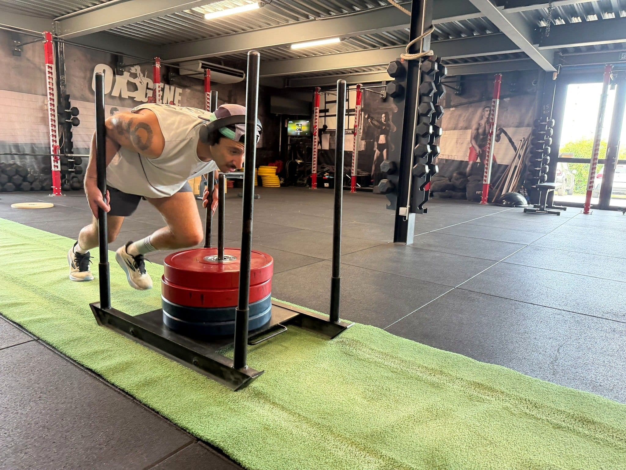 Athlète en plein Sled Push dans la salle Training OXYGÈNE Fitness