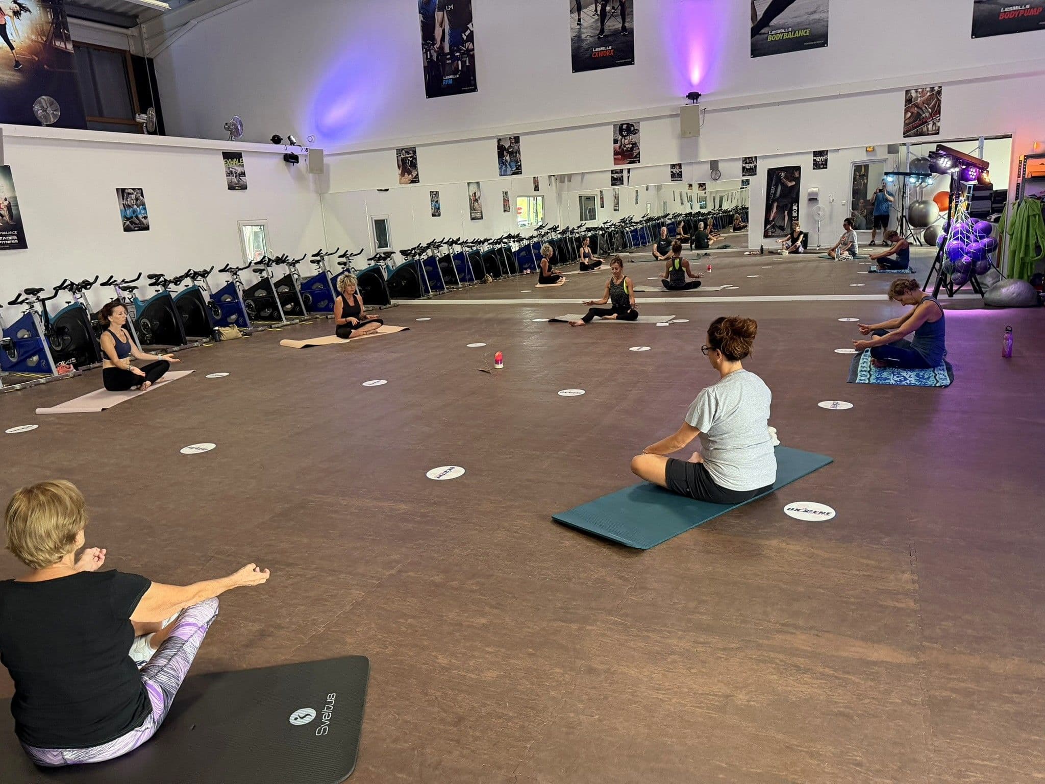 Séance de Stretch avec adhérents assis sur tapis dans la salle Fitness OXYGÈNE