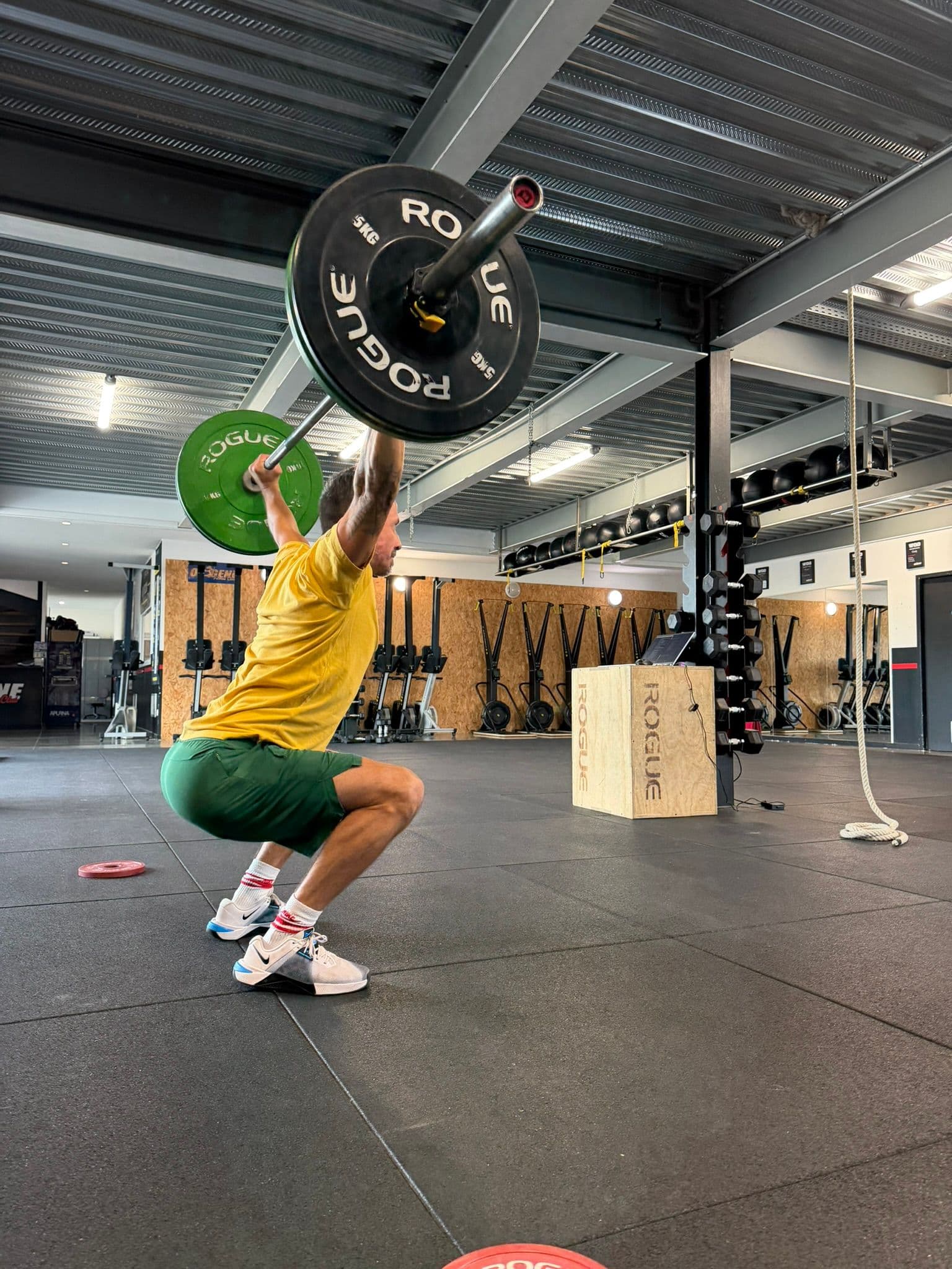 Pratiquant réalisant un squat avec une barre maintenue au-dessus de la tête dans la salle Training d’OXYGÈNE Saint-Macaire.