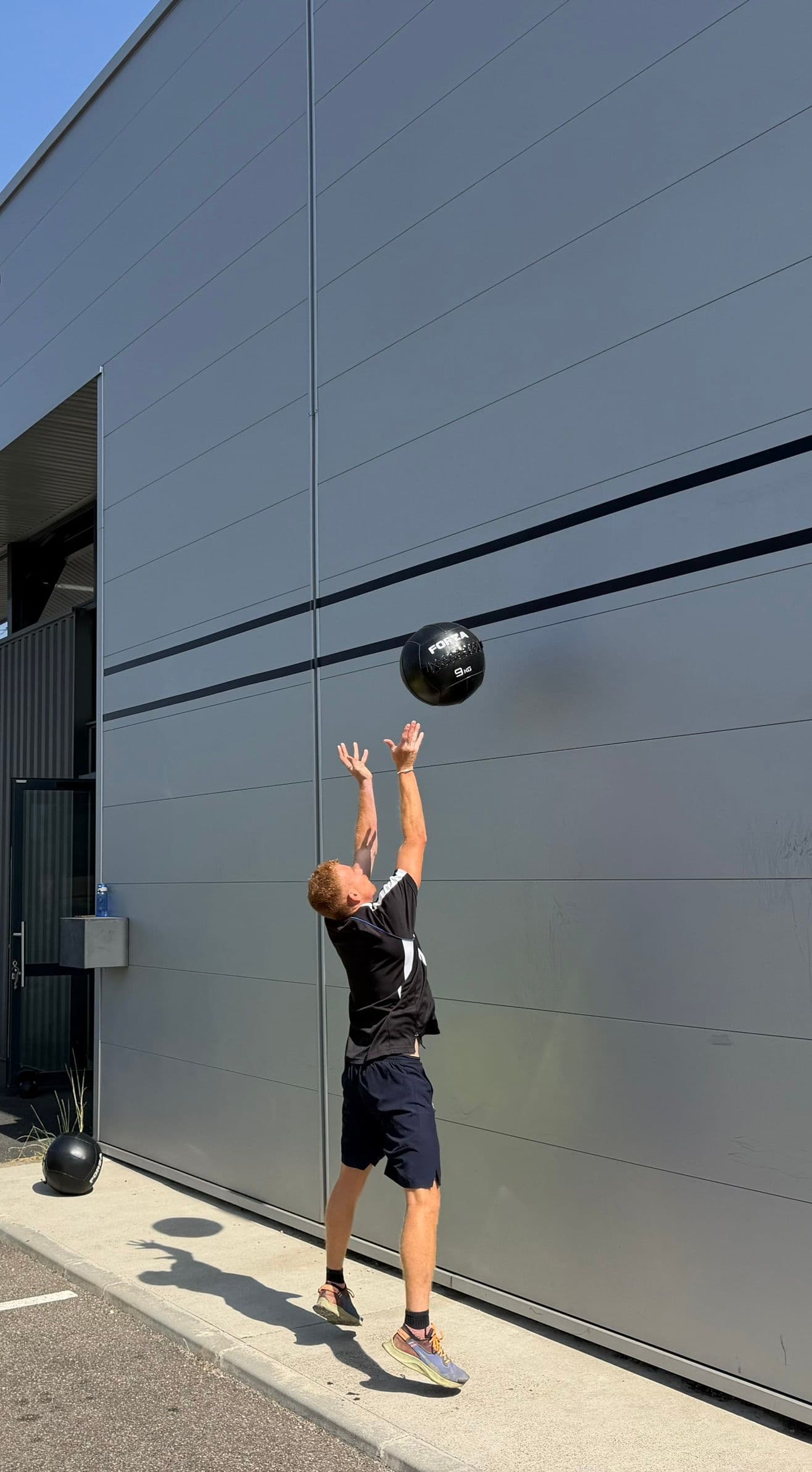 Un pratiquant lance un ballon lesté contre le mur extérieur d’OXYGÈNE Saint-Macaire.